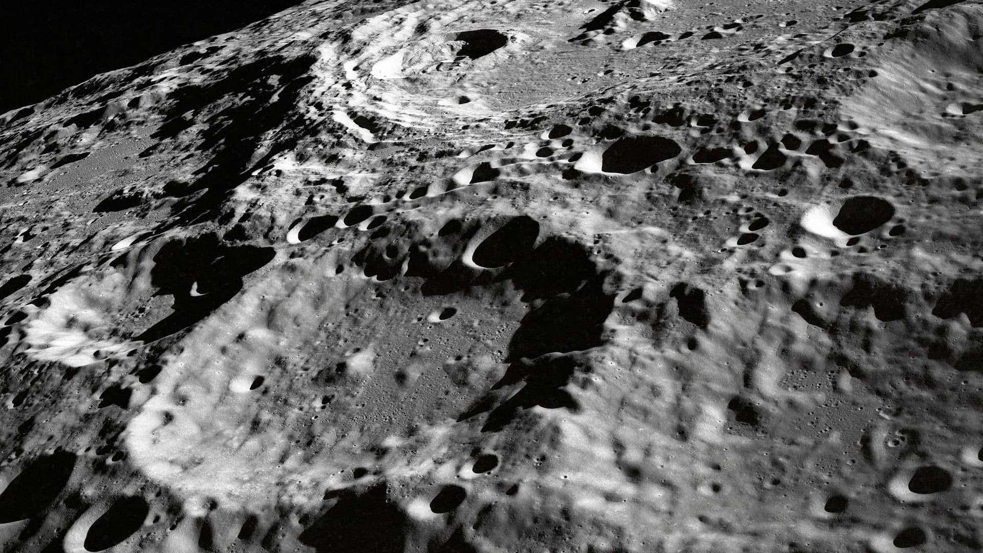 The ridged surface of the Moon, with craters and mountains visible.